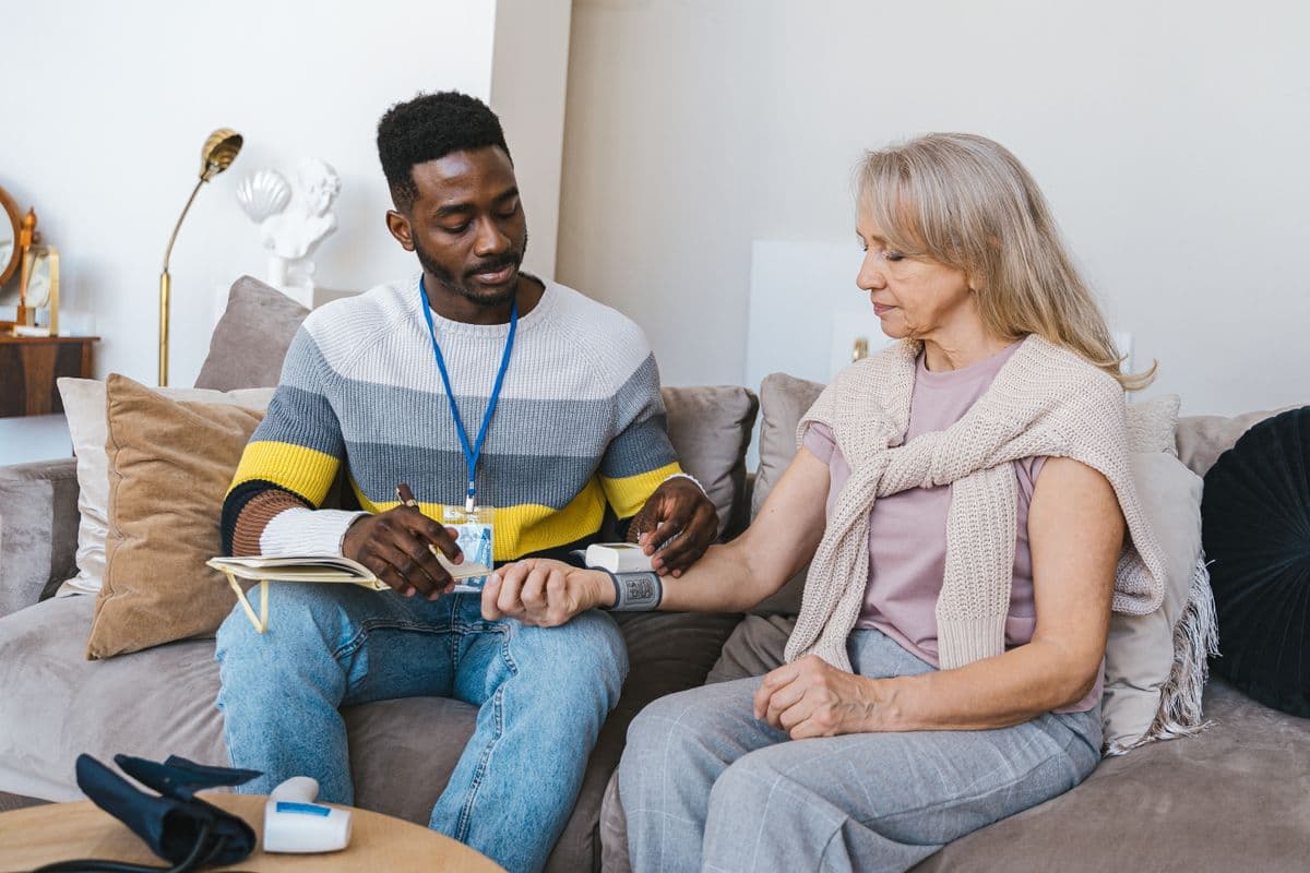 Caregiver checking a patient's blood pressure during a home visit